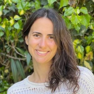 Una foto del autor sonriendo a la cámara con vegetación de fondo