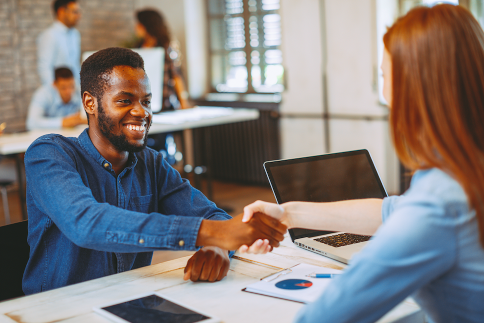 A job candidate shaking hands and smiling at an interviewer