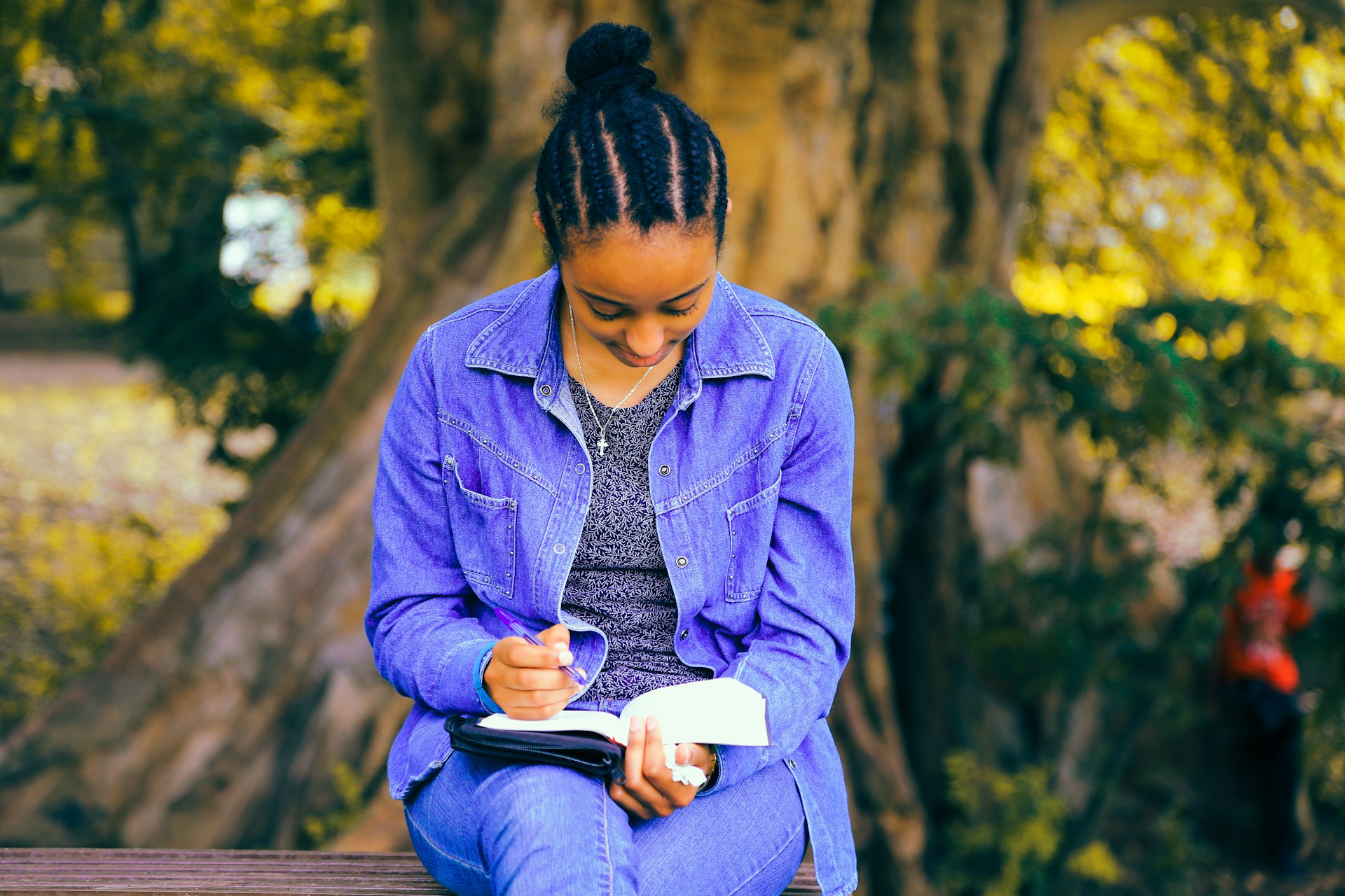 Una mujer en un parque estudiando un cuaderno con un bolígrafo