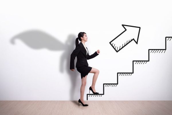 A women in office attire climbing stairs with her shadow wearing a cape